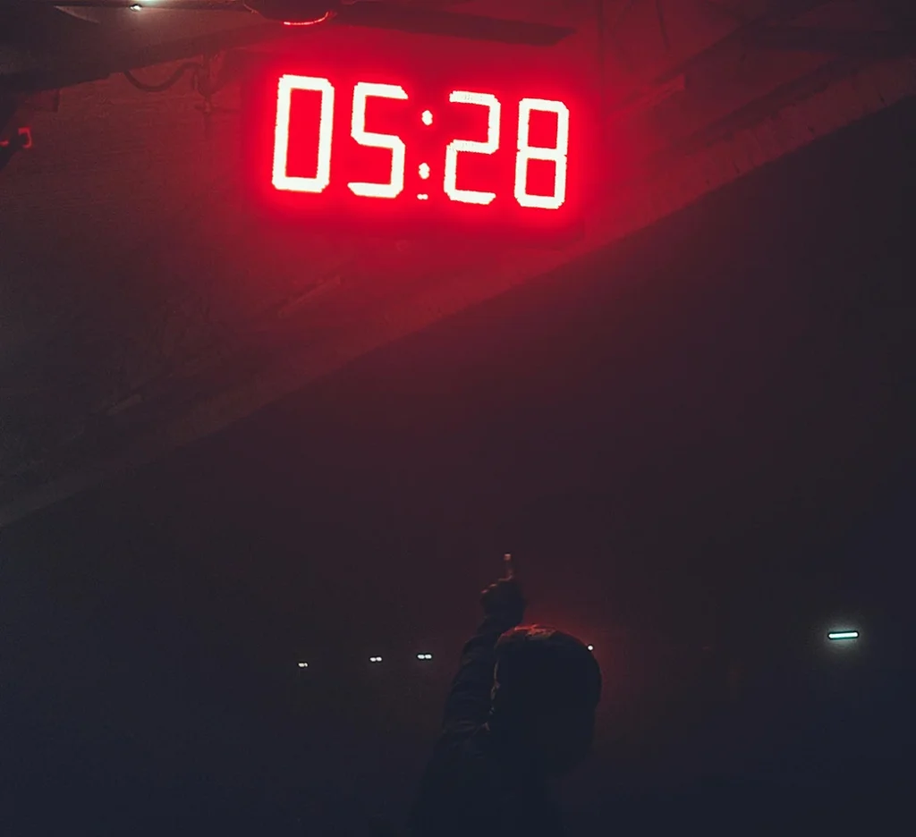 A person in a dark room pointing to a glowing red LED countdown timer