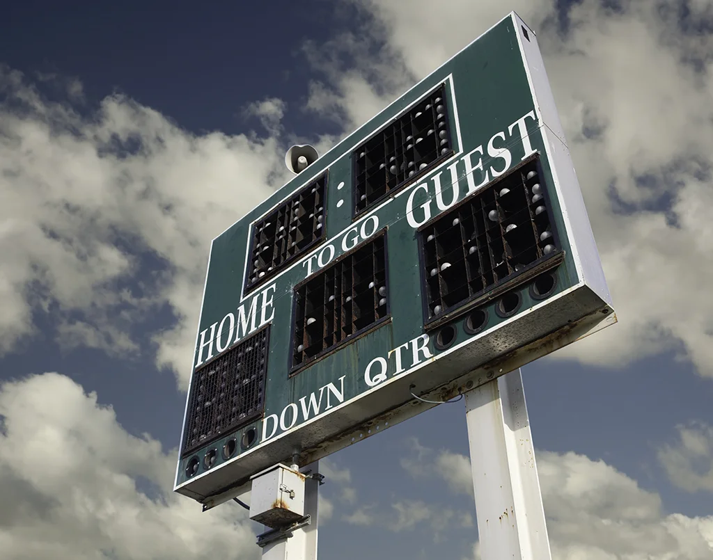 Image of an old scoreboard against a cloudy blue sky.